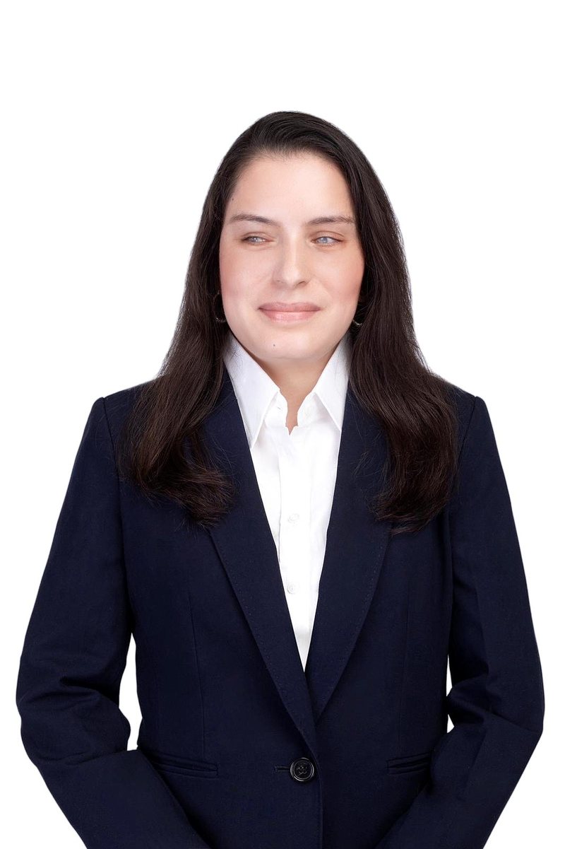 Priscilla Garces, smiling slightly, in a navy blazer over a white collared shirt, photographed against a white background.